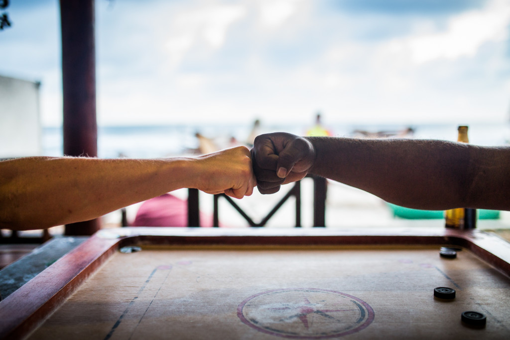 Local legend Podi and Surfer Jake fist bump during a game of Carrom